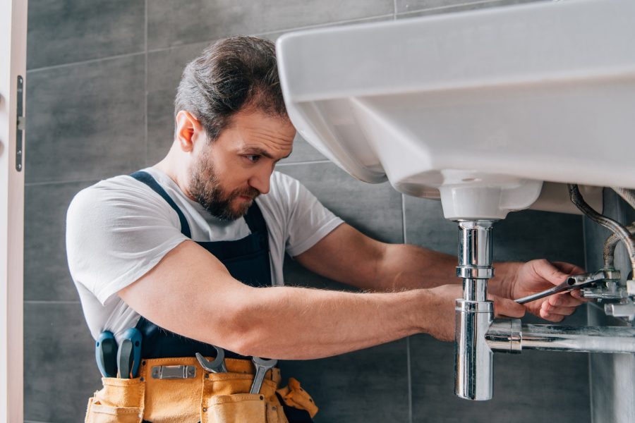 focused-male-plumber-in-working-overall-fixing-sink-in-bathroom.jpg